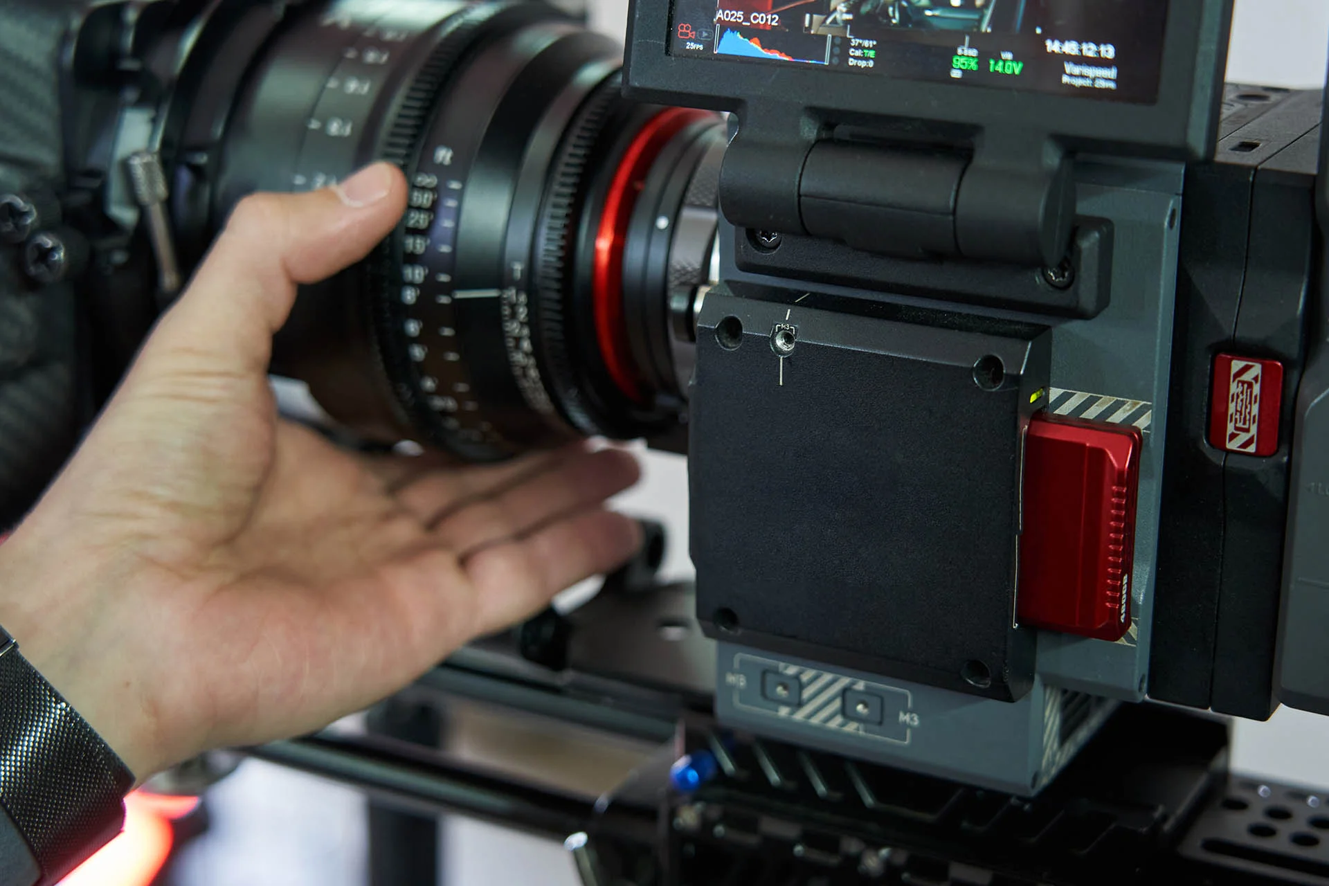 caucasian man's hand twists the lens focus on a professional movie camera